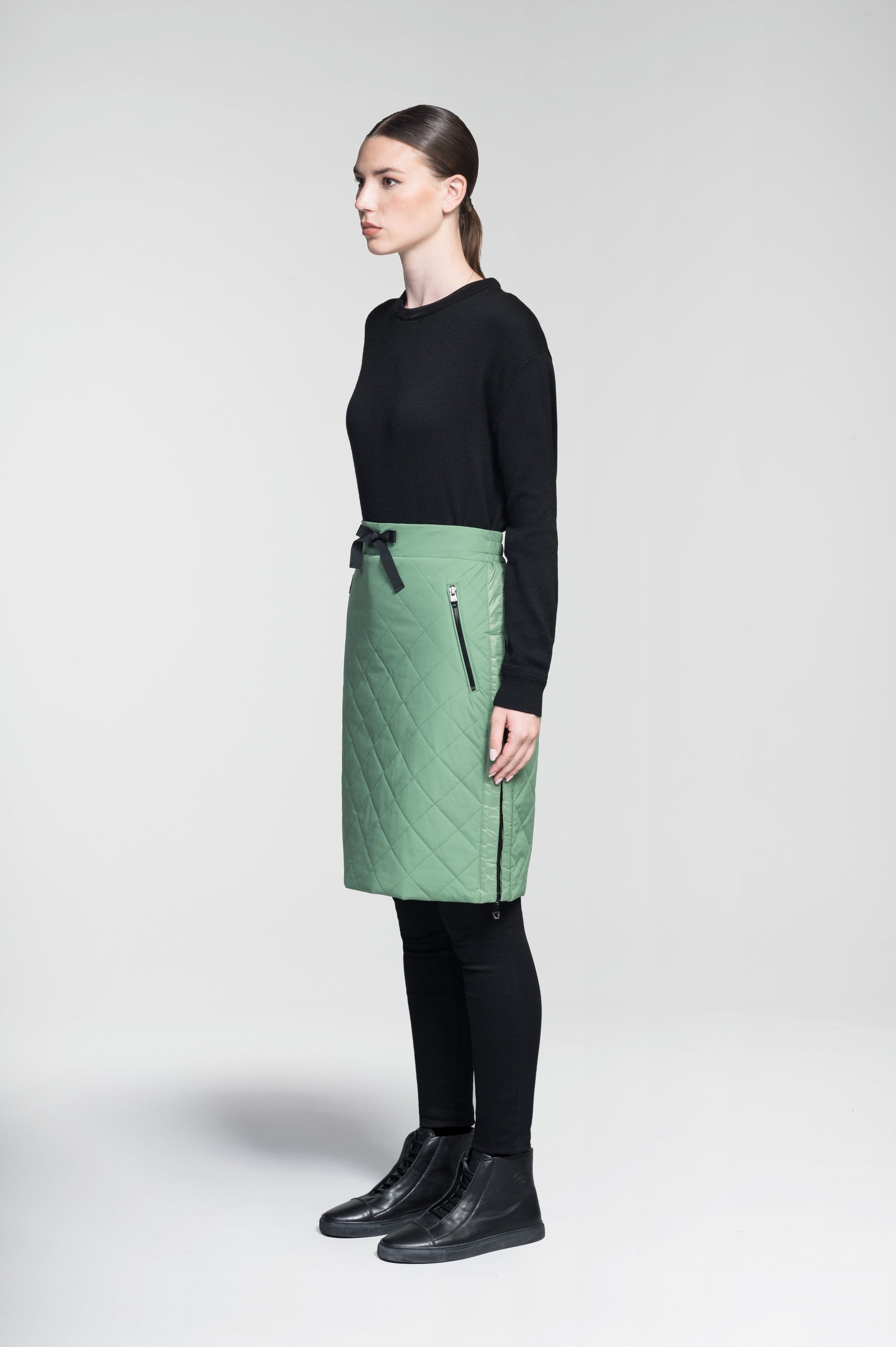 Phora Women's Tailored Skirt in knee length, premium stretch ripstop and contrast cire technical nylon taffeta fabrication, premium 4-way stretch, water resistant Primaloft Gold Insulation Active+, elasticated waistband with grosgrain ribbon drawstrings, two zipper pockets at waist, and zipper closure gusset at side seams, in Comfrey