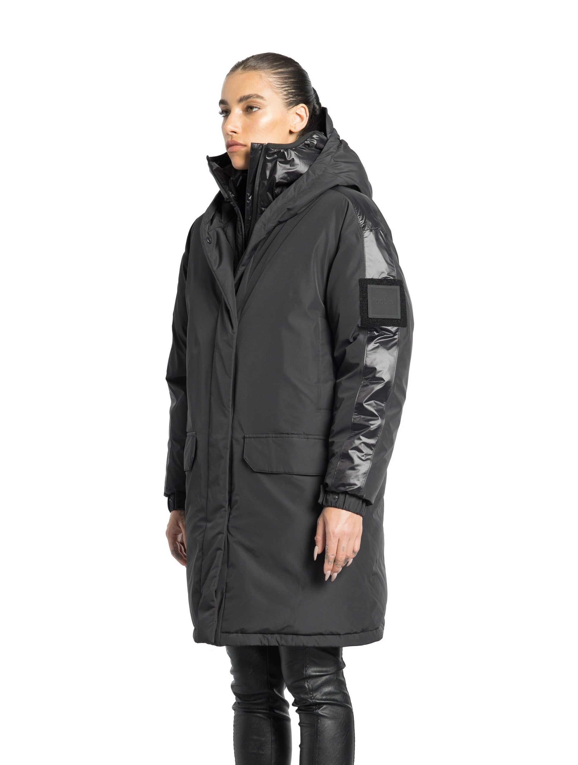 Slyn Women's Performance Parka in thigh length, premium 3-ply micro denier and cire technical nylon taffeta fabrication, Premium Canadian origin White Duck Down insulation, non-removable down-filled hood, inner hooded gilet, two-way centre-front zipper with magnetic closure wind flap, fleece-lined pockets at chest and waist, pit zipper vents, in Black
